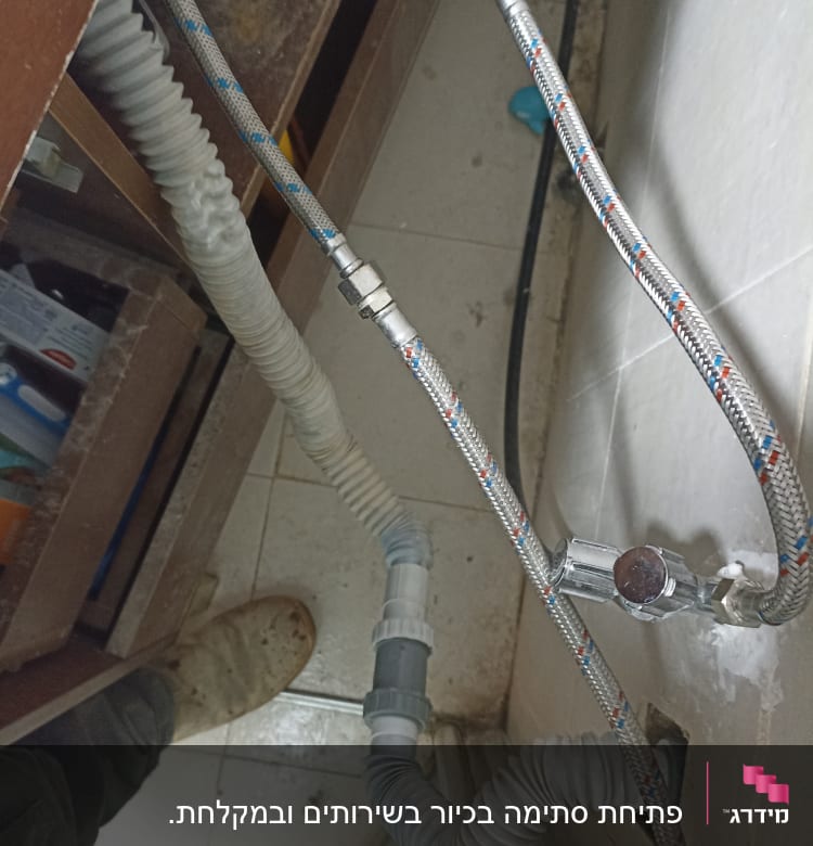 צינורות מים וגומי מתחת לכיור במטבח